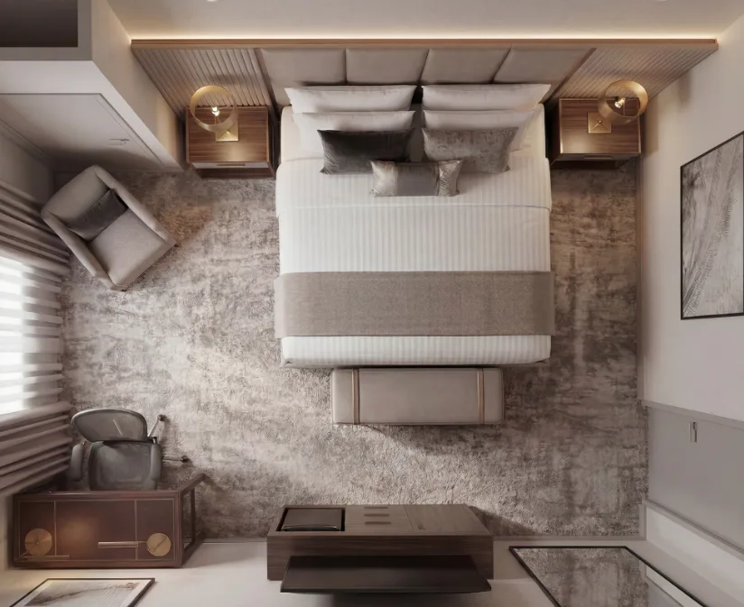 Overhead view of a hotel guestroom: upholstered headboard wall, nightstands, lounge chair, desk and luggage bench