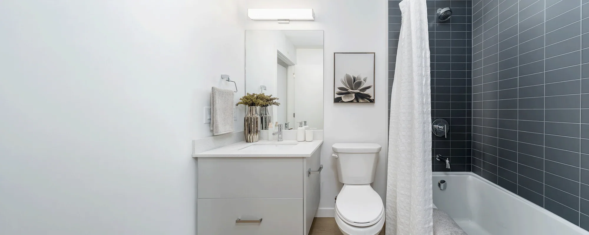 Modern hotel bathroom with frameless glass shower enclosure and stone surround