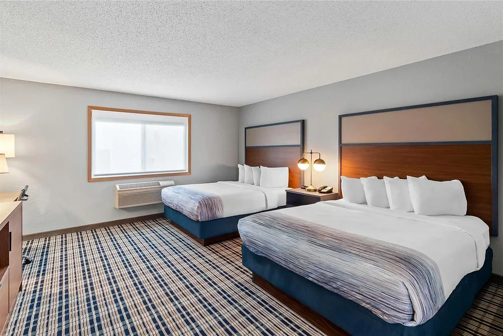 AmericInn by Wyndham Crookston — double-queen guestroom with wood headboards and nightstand