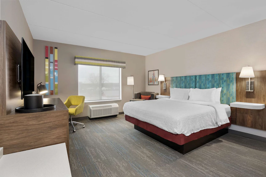 Hampton Inn & Suites Cornwall — king guestroom with upholstered headboard, art panel and desk