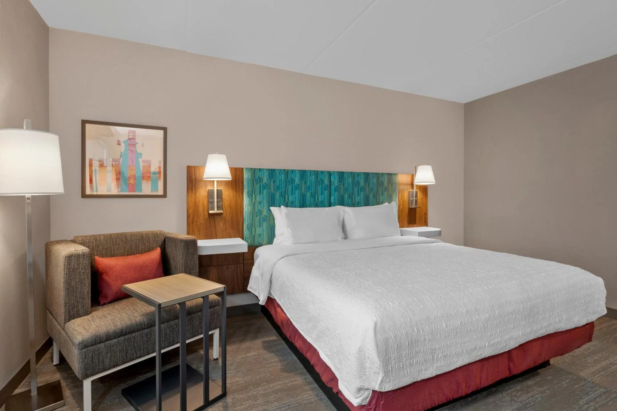Hampton Inn & Suites Cornwall — king guestroom with lounge chair and framed artwork