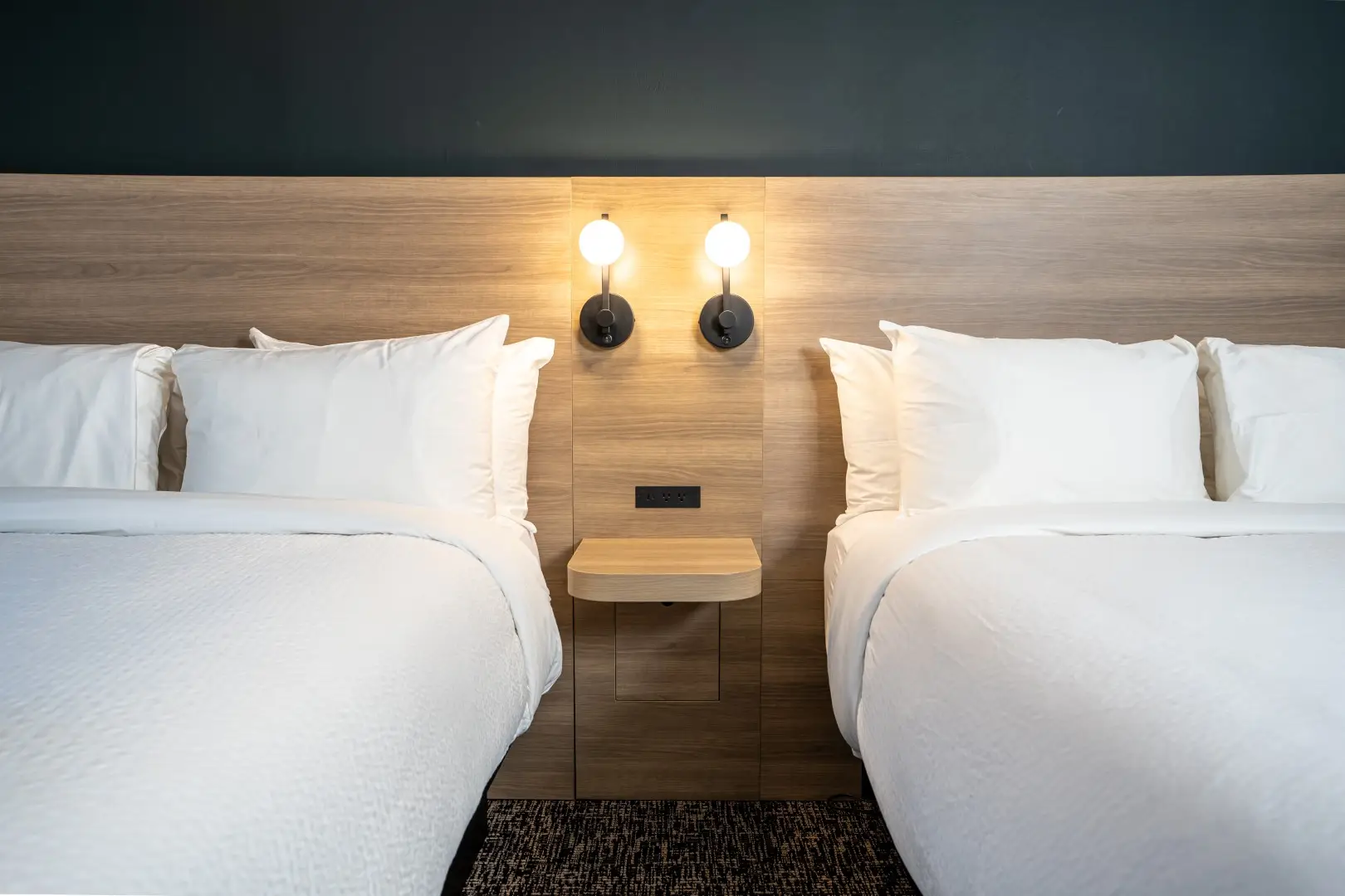 Northwinds Hotel Revelstoke — double-queen headboard detail with floating nightstand and sconces