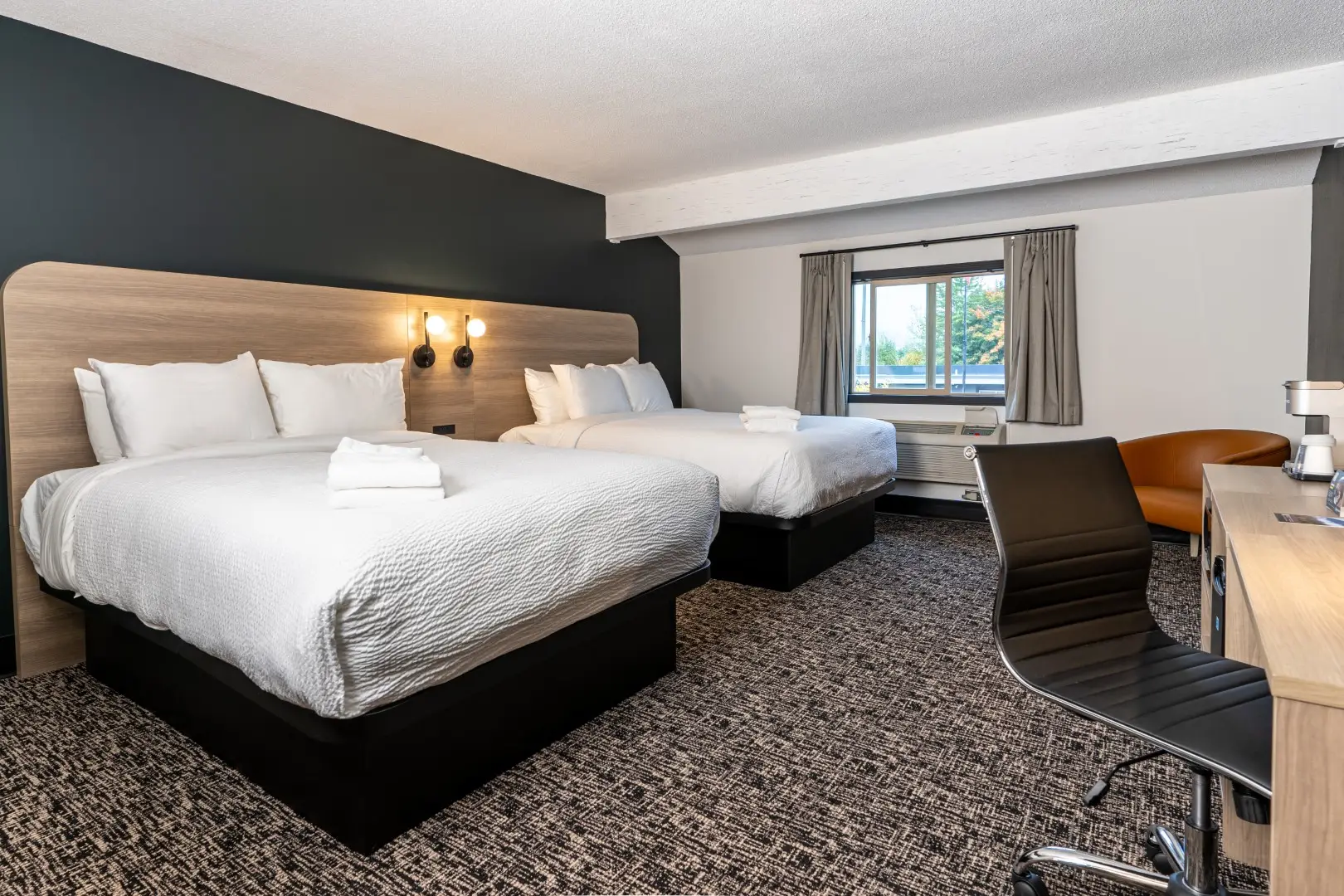 Northwinds Hotel Revelstoke — double-queen room with wood headboards, accent chair and desk