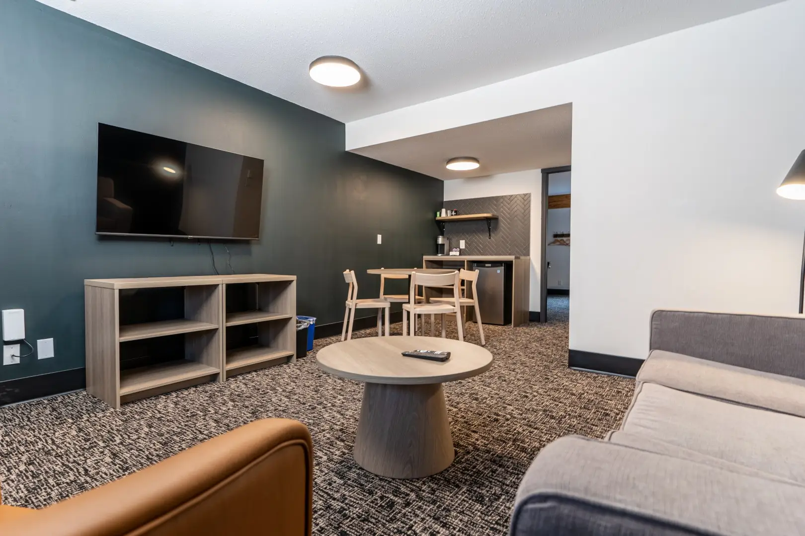 Northwinds Hotel Revelstoke — suite lounge with sofa, leather accent chair and canvas artwork