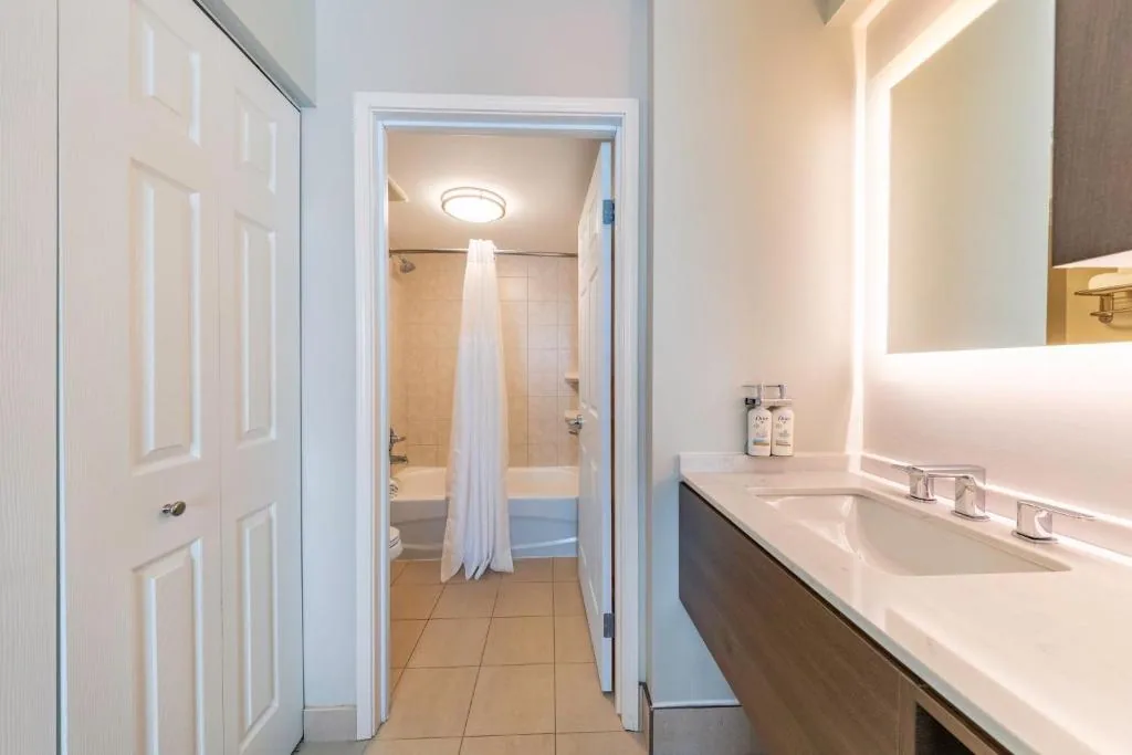 Staybridge Suites Guelph — bathroom vanity with floating wood cabinet and backlit LED mirror