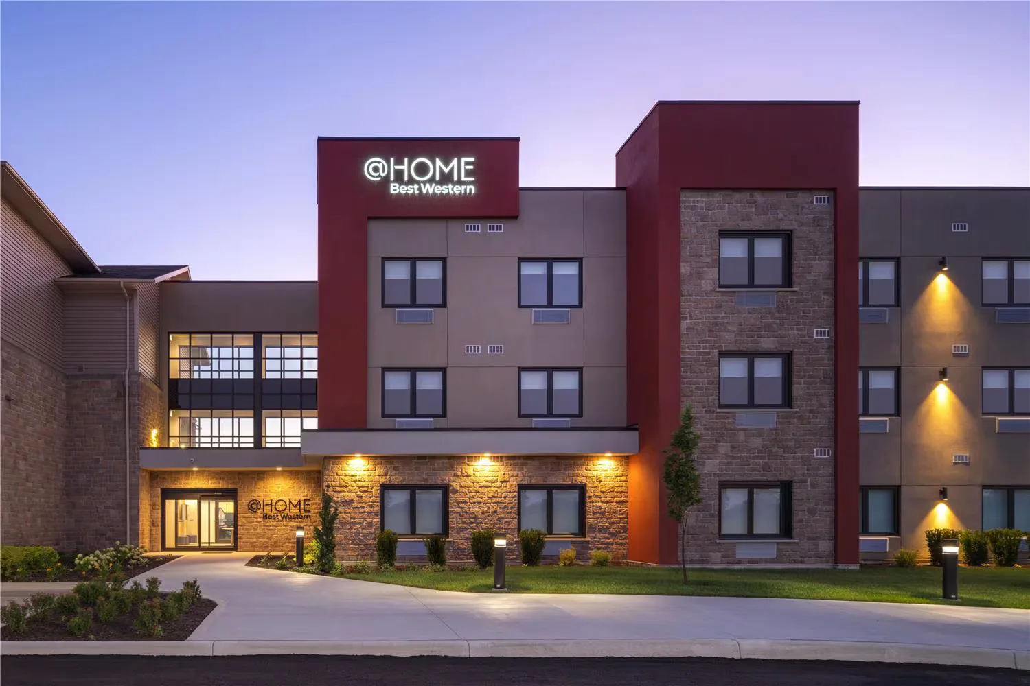 @HOME by Best Western Walkerton — hotel exterior at dusk with illuminated @HOME by Best Western signage