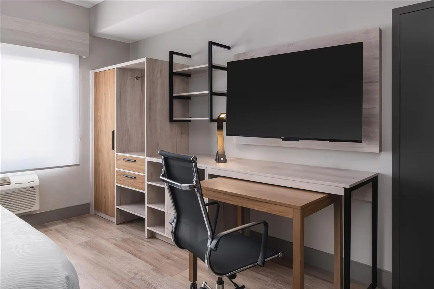 @HOME by Best Western Walkerton — desk, TV panel and open shelving in light-oak laminate
